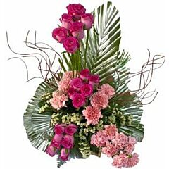 One sided arrangement of pink roses and pink carnations in a basket